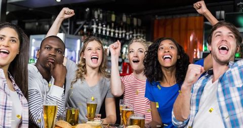 Diverse Friends Celebrating with Drinks and Gold Confetti in Lively Bar