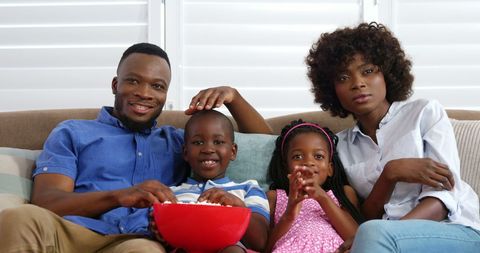 Happy Family Watching TV and Eating Popcorn Together