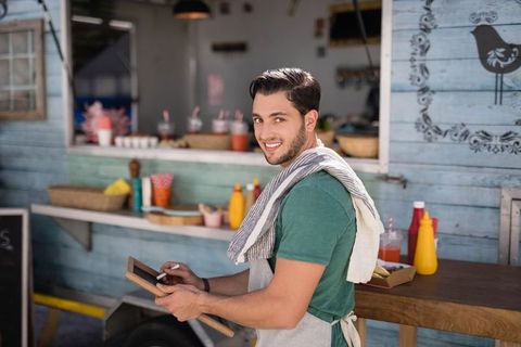 Cheerful food truck worker using digital tablet