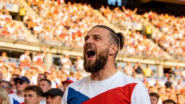 Bearded fan shouting and cheering during live match in packed sunny stadium stands