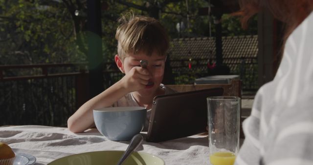 Young Boy Eating Breakfast Outdoors with Tablet - Download Free Stock Images Pikwizard.com