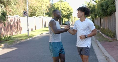 Diverse male friends fist bumping in street during workout