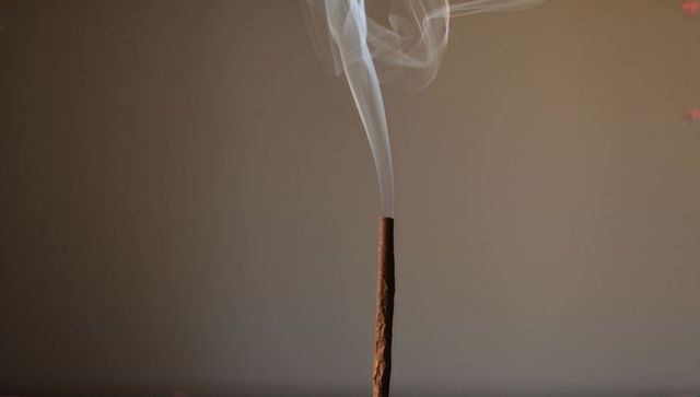 Minimalist burning incense stick releasing delicate white smoke plume for calm interiors