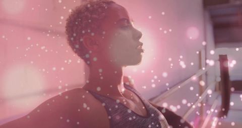 Dancer stretching at barre backlit by pink bokeh glow and soft light