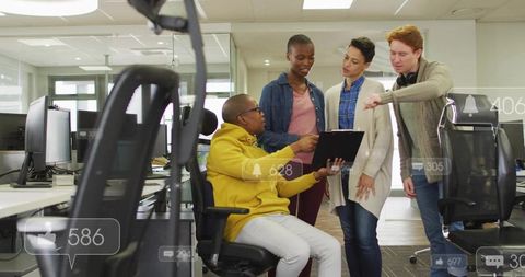 Diverse team collaborating around tablet in modern open-plan office with notifications