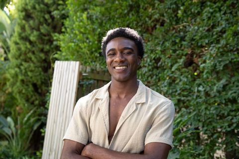 Happy Man Smiling in Lush Garden with Crossed Arms