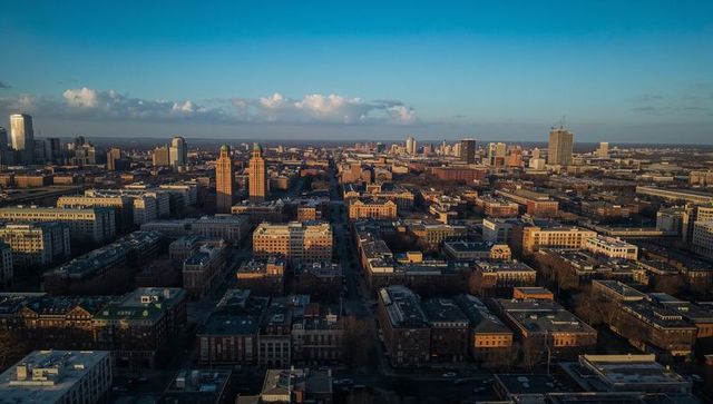 Aerial city grid at golden hour showing downtown rooftops, towers and distant skyline