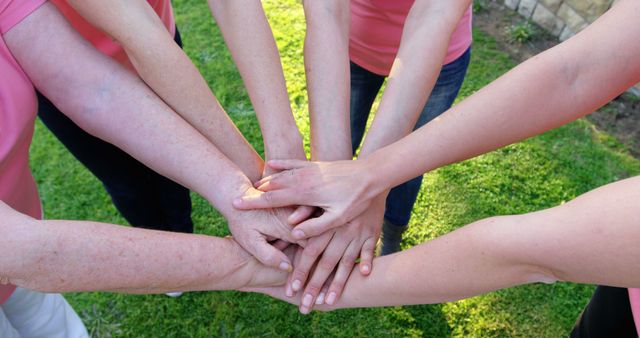 Women joining hands in a circle creating symbol of unity and support. Seen from above, expressive gesture conveys teamwork and togetherness outdoors. Great for illustrating concepts of collaboration, community support, empowerment, and social bonding. Ideal for articles, brochures, campaigns on women empowerment, teamwork, and community support.