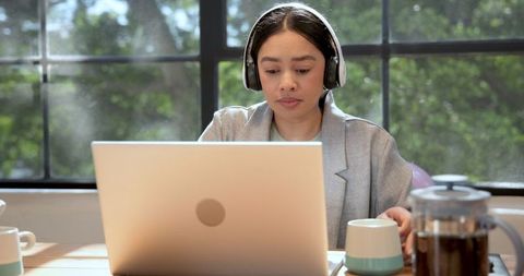 Motivated Professional Woman Using Laptop and Headphones at Office Desk