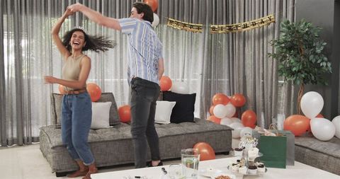 Joyful couple dancing at home birthday celebration