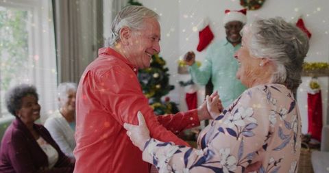 Senior couple dancing at holiday party in cozy living room surrounded by friends