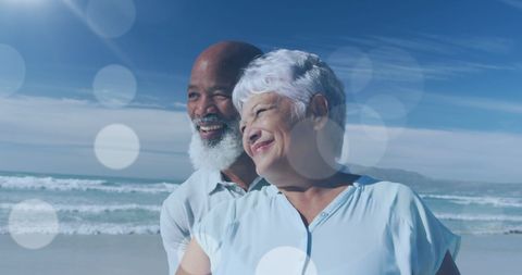 Happy Senior Couple Embracing at Beach in Warm Sunlight
