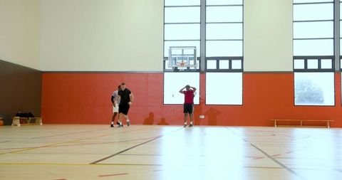 Male basketball players gathering at indoor court wall for casual pickup training