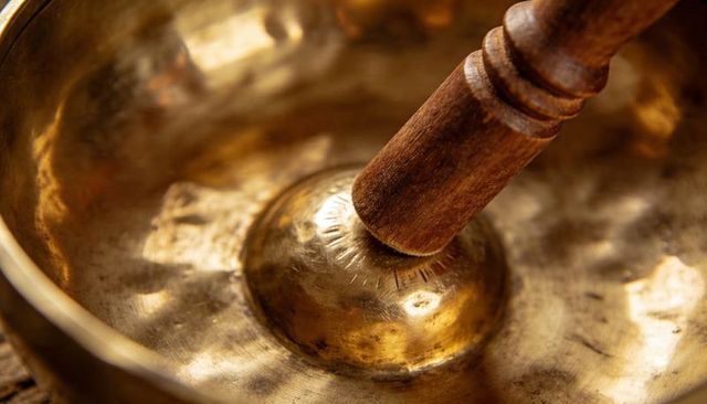 Bronze singing bowl resonating with wooden mallet creating warm vibrations