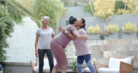 Multigenerational women hugging after outdoor workout on sunlit patio, friendship wellness