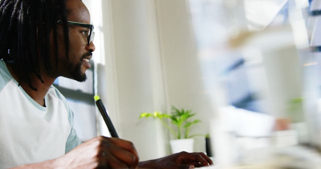 Afro-American man writing at desk in modern office - Download Free Stock Images Pikwizard.com