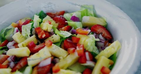 Showing vibrant fresh pineapple strawberry salad with lettuce, cucumber, red onion, pepper