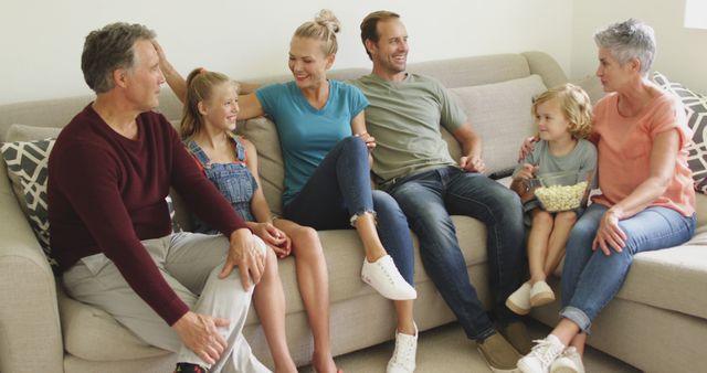 Happy caucasian family relaxing on couch talking and eating popcorn. three generation family spending time together at home.