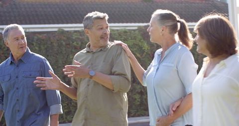 Diverse Middle-Aged Friends Socializing Outdoors Next to Garden Hedge