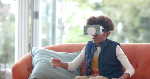 Boy Exploring with VR Headset on Sofa in Bright Room