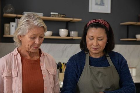 Mature women cooking together in modern kitchen, collaborating on home meal preparation