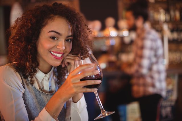 Portrait of young woman having red wine in pub