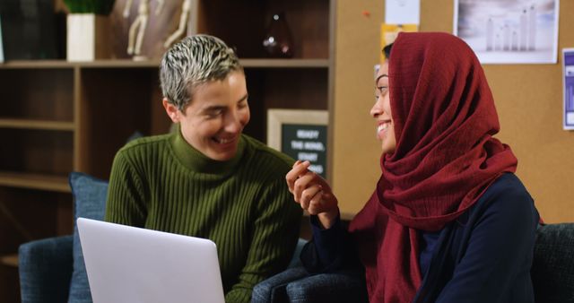 Women from different cultural backgrounds are collaborating, suggesting effective teamwork and inclusivity in a modern office environment. This image may be used for promoting diversity, professional collaboration, women's empowerment, and workplace dynamics.