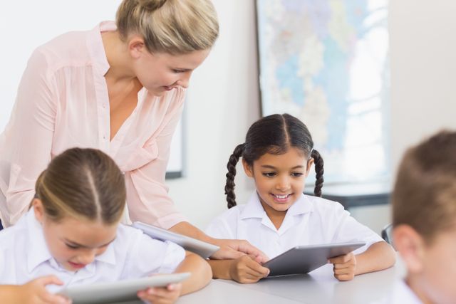 Teacher teaching school girl on digital tablet in classroom at school