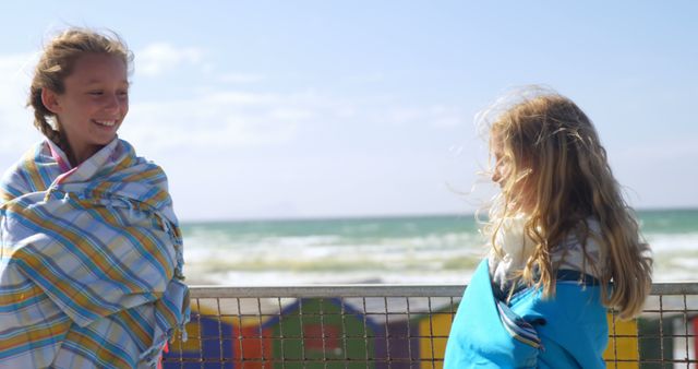 Two young girls wrapped in blankets on a windy beach - Download Free Stock Images Pikwizard.com