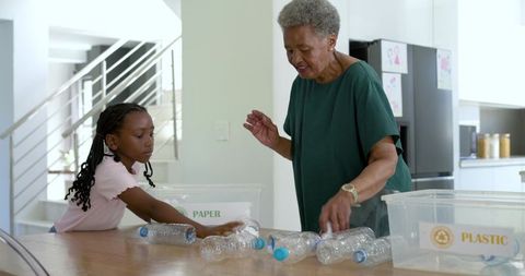Grandparent Teaching Grandchild Recycling with Plastic Bottles in Sunlit Kitchen