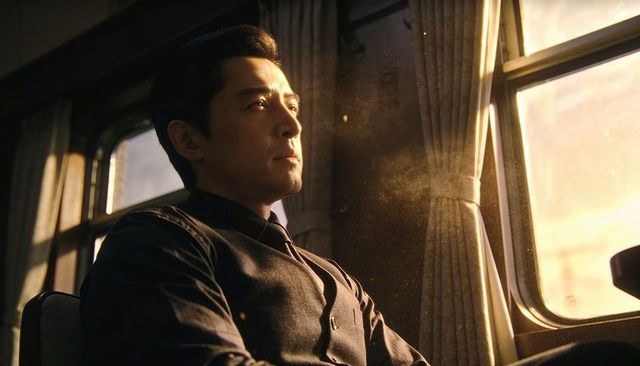 Contemplative asian man gazing out sunlit train window at golden hour, vintage railcar