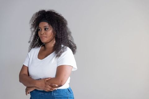 African american woman standing arms crossed white tee denim, calm studio portrait