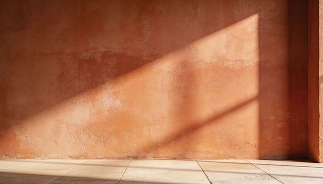 Terracotta plaster wall casting triangular sunlit shadow on tiled floor, warm minimalist