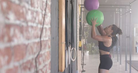 Woman Lifting Exercise Balls in Modern Gym for Fitness and Strength Training