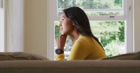Thoughtful Woman Looking Out Window on Relaxing Day at Home