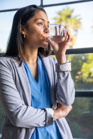 Businesswoman Hydrating in Bright Office with Natural Views