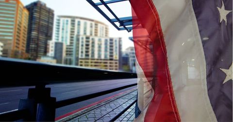 American Flag Overlooking Busy Urban Highway and Cityscape