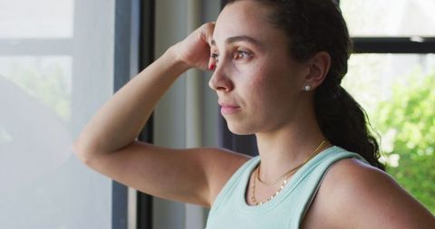 Thoughtful Woman Gazing Out Window in Bright Home Setting