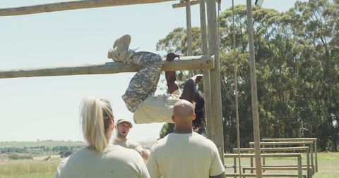 Soldier mastering obstacle course with team support