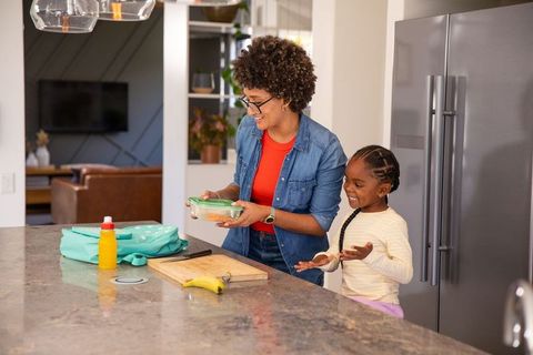 Mother and daughter preparing school lunch in modern kitchen