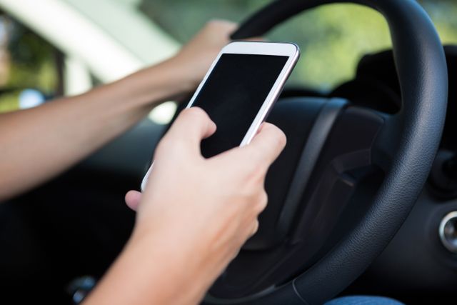Woman using mobile phone while driving car. Represents distracted driving and road safety issues. Useful for campaigns on driving safety, technology use, and traffic regulations.
