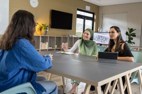Multicultural female team collaborating in modern office meeting, design planning session
