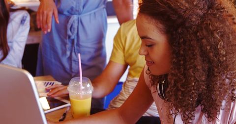 Young Woman Joyfully Engaging with Laptop at Bustling Café