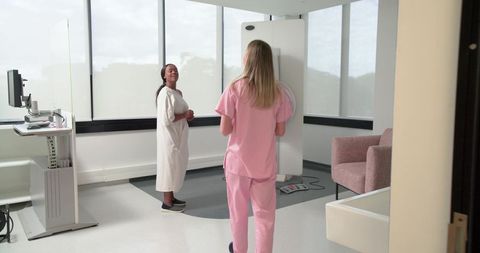 Radiography Technician Positioning Diverse Female Patient Against Digital X-Ray Panel