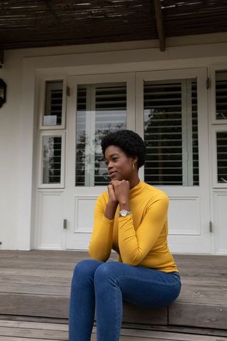 Woman Contemplatively Sitting on Porch Steps in Casual Outfit