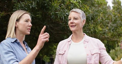Middle-Aged and Younger Woman Discussing Garden Plans Outdoors While Pointing and Smiling