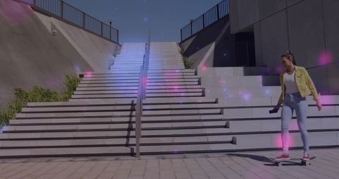 Young woman balancing on skateboard while holding phone by urban stairs at twilight with purple glow