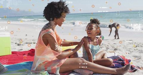 Mother applying sunscreen to daughter on sunny beach towel during family seaside vacation