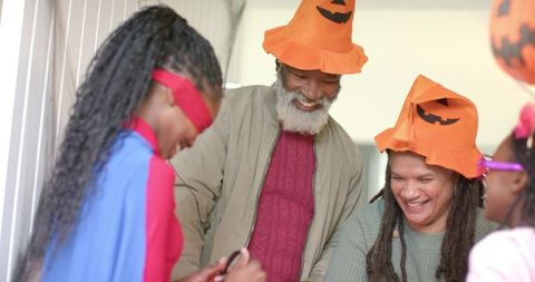 African american family in pumpkin hats playing blindfold game at cozy halloween party