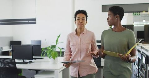 Two businesswomen discussing projects in modern office environment